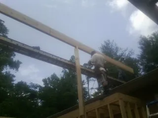 Carpenter setting a ridge beam over a new addition frame — Ice Dam Removal by Roofing Brothers in Maple