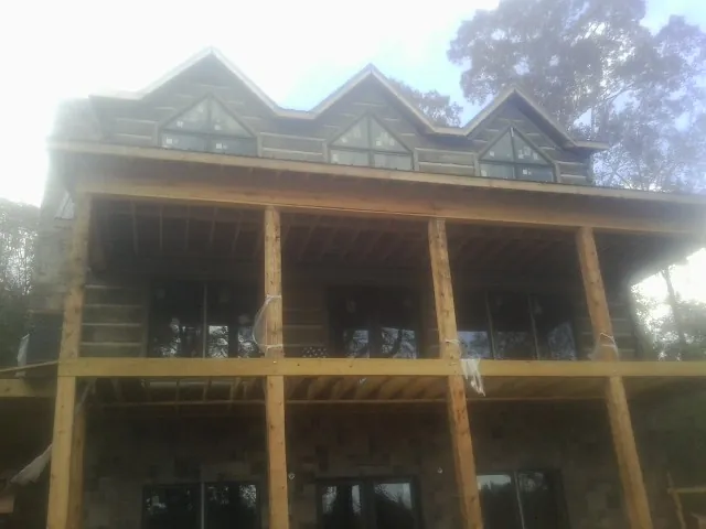 Dormers and porch framing on a large log home under construction — Roof Coating work by our crew in Maple