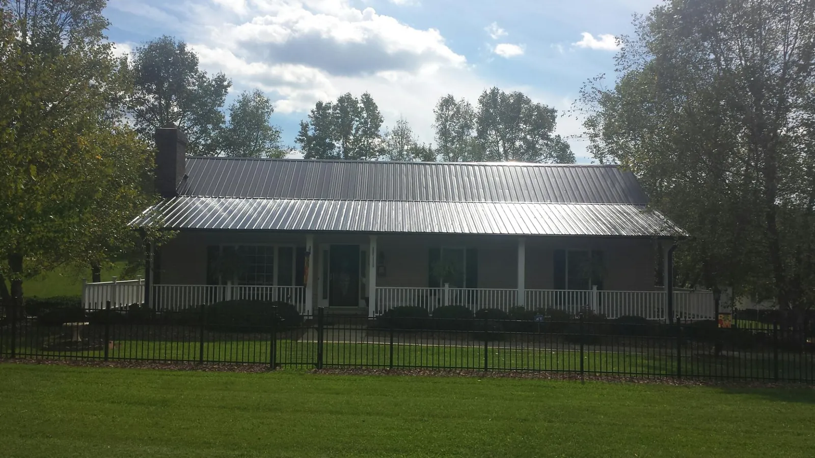 Gray metal roof on a brick ranch with a full width front porch — Gutter Guard Installation work by our crew in Maple